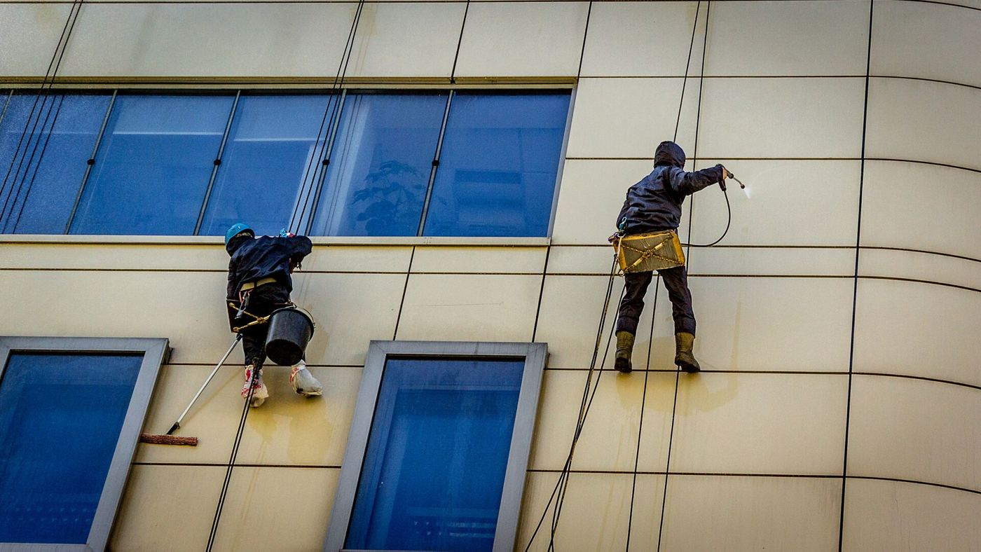 Two technicians cleaning a commercial facade (placeholder photo)
